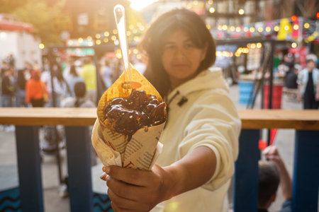 woman holding Belgian french fries with sauce at food court. street food festival on background blurredの写真素材