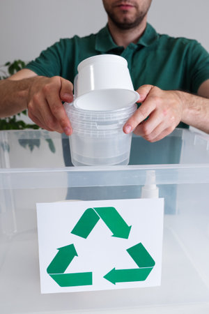 male sorting plastic trash and putting waste in recycling container indoors at home. Environmental protection and zero waste concept.の写真素材