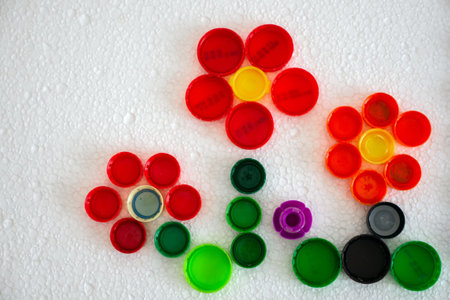 Flowers mosaic decoration made of colorful plastic bottle caps. Handmade crafts. Recycling art.