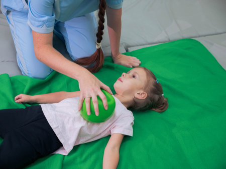 Physical therapist working with little girl in sensory room. Exercising with weighted ball and pressure to help kid relax in a therapy center. sensory integration sessionの写真素材