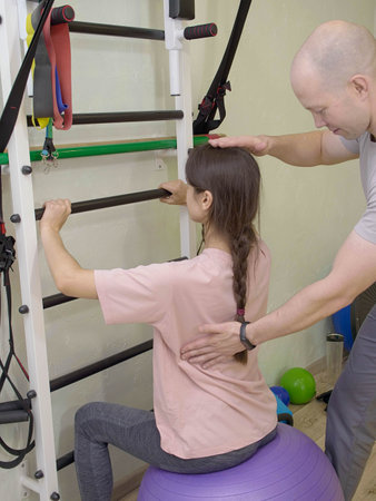 Physical therapist assisting young woman remove shoulders and back pain in the gym on gymnastic...