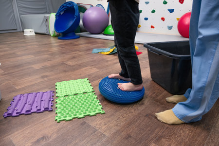 Kid on Sensory Mat Massage during sensory integration session. child girl in rehabilitation centre with physiotherapist doing orthopedic correction.の写真素材