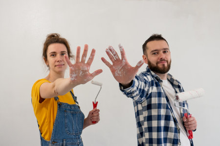 couple posing during repair works painting wall together and standing with tools. Happy family make renovation DIY renew home concept. decorating work in new apartmentの写真素材