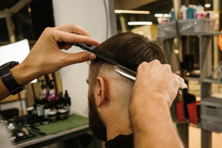 Barbershop. Unrecognizable male barber hands making customer Fashionable haircut in Modern style...