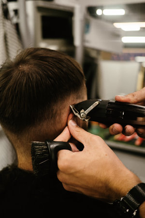 Barbershop. Unrecognizable male barber hands making customer Fashionable haircut in Modern style barber shop. Bearded Man client visit gentleman grooming beauty salon for hairstyle careの写真素材