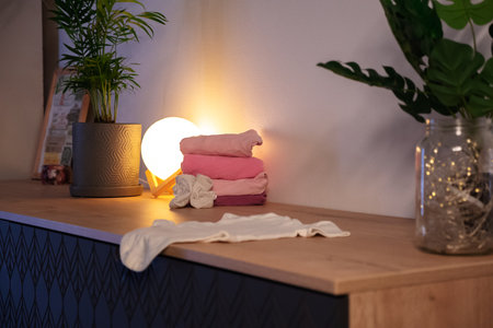 a stack of pink baby clothes in warm muted light. anticipation getting ready for the baby girl at homeの写真素材