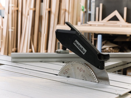 A circular saw rests on a workbench with wood panels in the background. Concept of precision, construction, and DIY projects, highlighting craftsmanship. Smolevichi, Belarus - September 25, 2025のeditorial素材