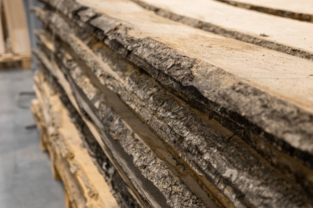 Stacked logs with textured bark fill the frame, showcasing natural wood grain. Concept of sustainable forestry, raw materials, or rustic construction is conveyed.の写真素材