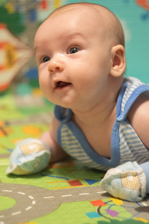 Newborn Baby lying on stomach in scratch mittens. Protect hands from accidental scratches. Babycare and safetyの写真素材