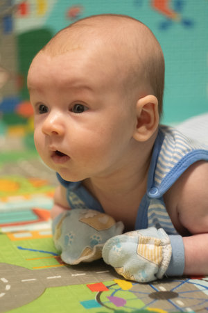 Newborn Baby lying on stomach in scratch mittens. Protect hands from accidental scratches. Babycare...
