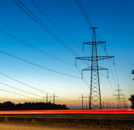 Pylons and electricity power lines at night with traffic lights
