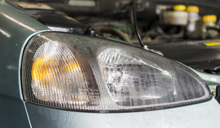 Car headlights close up image with rain drops as background