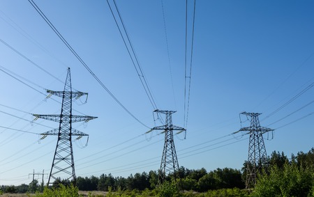 Electricity pylons going into the distance over summertime countryside.