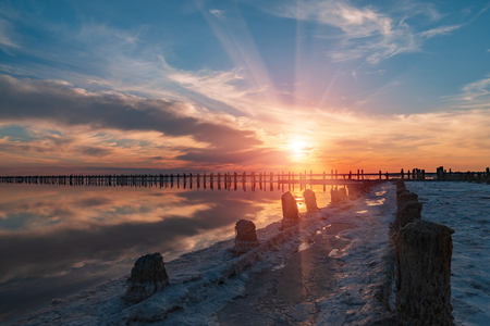 sunset on a pink salt lake, a former mine for the extraction of pink salt. row of wooden pegs overgrown with saltの写真素材