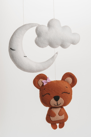 Colorful and eco-friendly children's mobile from felt for children. It consists of bear, moon and cloud toys. Handmade on white background.の写真素材