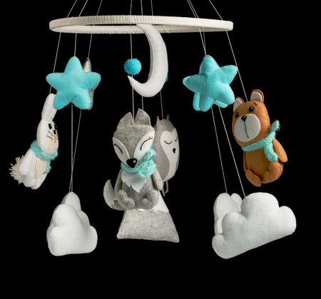 Colorful and eco-friendly children's mobile from felt for children. It consists of bear, fox, owl, rabbit, mountain, stars, clouds and balloons toys. Handmade on black background.の写真素材