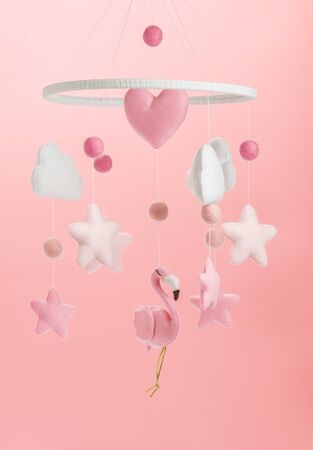 Colorful and eco-friendly children's mobile from felt for children. It consists of flamingo toys, clouds, stars and balloons. Handmade on pink background.の写真素材