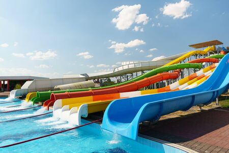 Water park, bright multi-colored slides with a pool. A water park without people on a summer day with a beautiful, cloudy blue sky.の写真素材