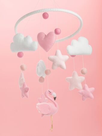 Colorful and eco-friendly children's mobile from felt for children. It consists of flamingo toys, clouds, stars and balloons. Handmade on pink background.の写真素材