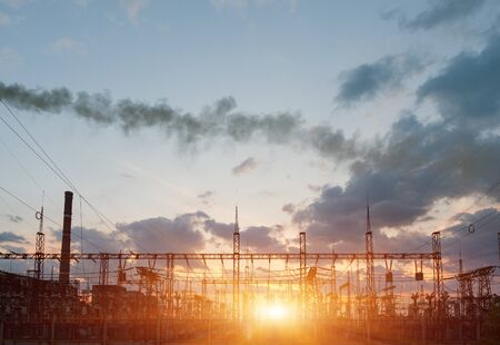 distribution electric substation with power lines and transformers, at sunset