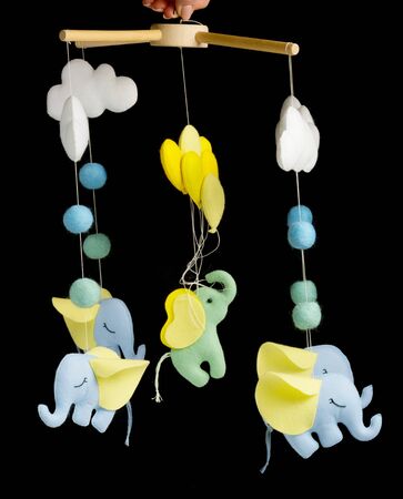 Colorful and eco-friendly children's mobile from felt for children. It consists of elephant, clouds and balloons toys. Handmade on black background.の写真素材