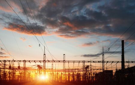 A silhouette of high voltage power lines against a colorful sky at sunrise or sunset.