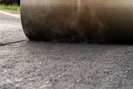 The vibratory roller levels the asphalt pavement.の写真素材