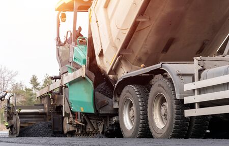 Paver machine is laying fresh asphalt on city road.の写真素材