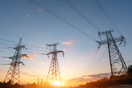 High-voltage power lines at sunset or sunrise. High voltage electric transmission tower.