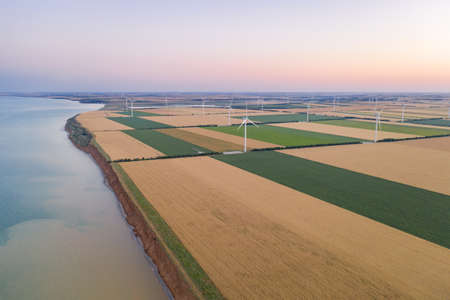 Sunset over the windmills. Wind turbines over fields of wheat and sunflowers.