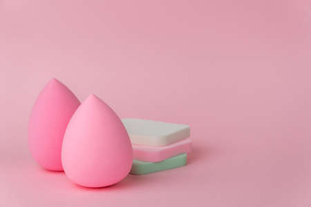 Sponges for applying makeup in the form of a drop or egg and flat sponges on a delicate pink background.の写真素材