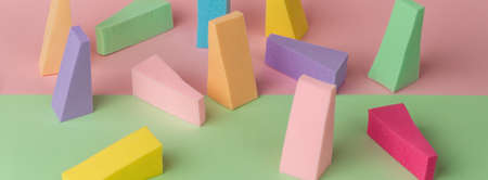 Top view of multi-colored sponges on different pastel-colored backgrounds. Abstract image.