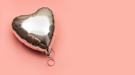One silver heart shaped air balloon on pink background with place for text.の写真素材
