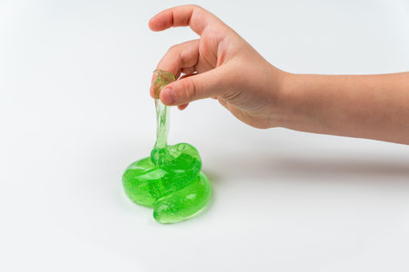Toy slime in the hand of a child on a light background. The child plays with mucus and develops fine...