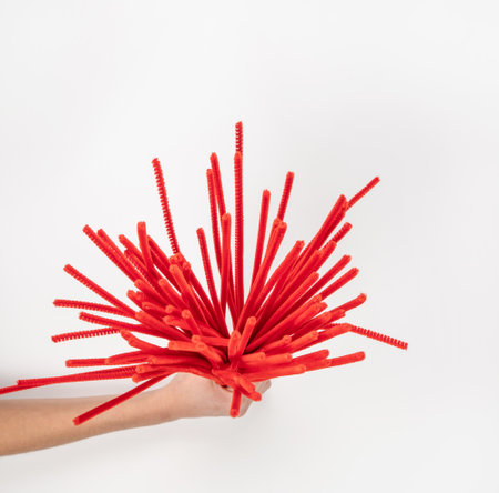 Red chenille wire on a light background. A lot of material for needlework in a woman's hand. Place for text.の写真素材