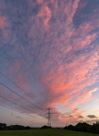 silhouette of high voltage power lines against a colorful sky at sunrise or sunset.の写真素材