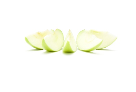 Green apple slices isolated over a white background の写真素材
