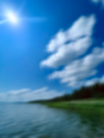 blurred summer background with blue sky and white clouds over the lakeの写真素材