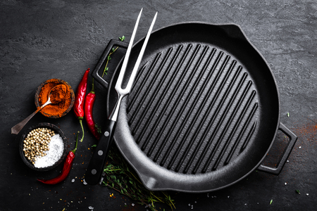 Empty cast-iron grill pan with ingredients for cooking on black background, top viewの写真素材