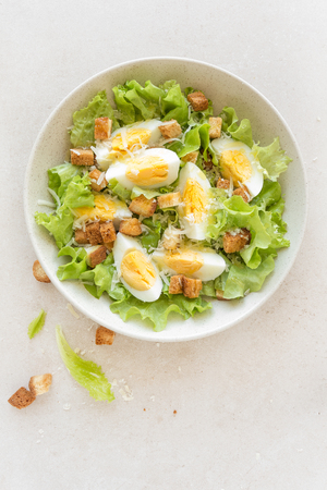 Caesar salad with eggs, lettuce and parmesan cheese on plate. Top viewの写真素材