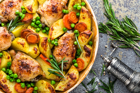 Chicken meat, thighs baked with potato, carrot and green peasの写真素材