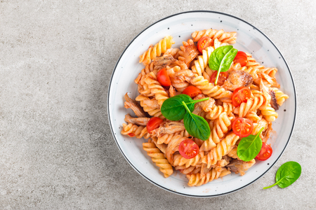 Pasta spirali stirred with fried pieces of chicken, cherry tomatoes and tomato sauceの写真素材