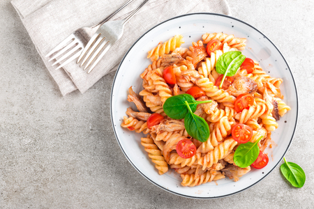 Pasta spirali stirred with fried pieces of chicken, cherry tomatoes and tomato sauceの写真素材