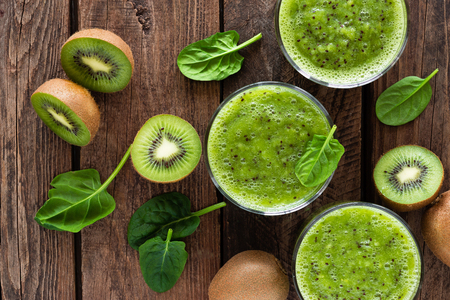 Kiwi smoothie drink of spinach leaves and fresh fruits on wooden rustic table, healthy detox diet の写真素材
