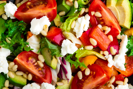 Vegetable dish, salad with avocado, pepper, tomato, italian mix, fresh lettuce, feta cheese and pine nuts. Healthy food. Top viewの写真素材