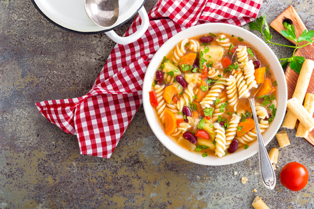 Minestrone soup. Vegetable soup with fresh tomato, celery, carrot, zucchini, onion, pepper, beans and pasta. Dish of italian cuisine.の写真素材