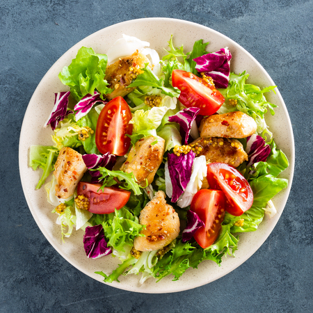 Fresh vegetable salad of tomatoes, cucumbers, italian mix, lettuce and grilled chicken breast. Fried chicken meat, fillet with salad. Healthy food. Flat lay. Top viewの写真素材