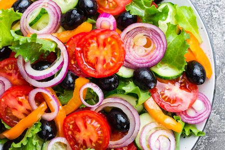 Greek salad. Fresh vegetable salad with tomato, onion, cucumbers, pepper, olives, lettuce and feta cheese. Greek salad on plateの写真素材
