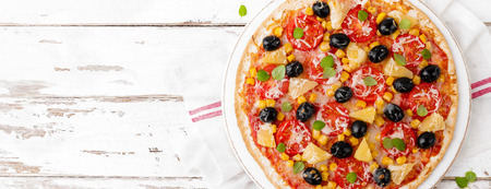 Pizza with tomatoes, mozzarella cheese, olives, corn and basil. Traditional italian cuisine. Top view. Bannerの写真素材