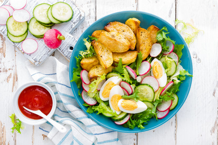 Delicious baked potato, boiled egg and fresh vegetable salad of lettuce, cucumber and radish. Summer menu for detox dietの写真素材